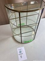 Full view of the semi-circular decorative glass shelf showing brass frame and glass panels with measurements indicated inside.