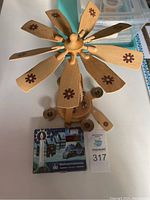 Top angle view of German wooden carousel showing wood blades decorated with brown snowflake-like patterns and candle holders around base.