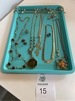 Full view of the jewelry lot showing necklaces, rings, and brooch on blue tray