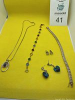 Full lot view showing necklace, 2 bracelets, and 3 pairs of earrings on a yellow background.