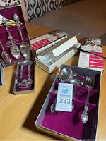 Multiple serving utensils out of box arranged on surface, showing shine and ornate handles matching Affection pattern.