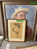 Large oil painting portrait of a man wearing a straw hat, with smaller framed ink sketch portrait leaning in front