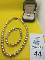 Overall view of pearl necklace, bracelet, ring and earrings on yellow background