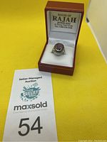 Full view of the ring in the open red jewelry box showing ring and box branding.