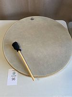 Full view of the Remo Ocean Drum positioned flat with mallet laid on top showing its size and surface.