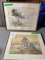 Both framed watercolor landscape paintings placed on table, showing sizes and general condition.
