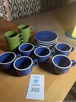 Top-front view of all cups, saucers, and green mugs arranged on a wooden surface