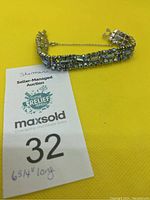 Front view of vintage Sherman rhinestone bracelet on yellow background with auction tag showing length and lot number