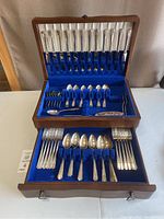 Full view of the open wooden box showing three tiers of cutlery pieces arranged neatly inside.