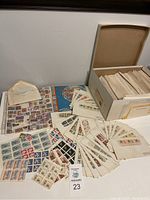 Overall view: storage box open with rows of envelopes, loose mint sheets and album cover visible