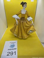 Full view of the Royal Doulton Stephanie figurine standing against yellow background, showing full dress and delicate posture.