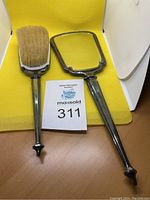 Photo showing the vintage sterling silver hand brush and hand mirror placed side by side on a yellow background