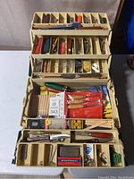 Full view of open plastic tackle box showing multiple compartments filled with woodworking and general tools
