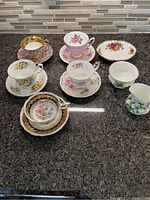 Full set of four teacups and five saucers displayed on countertop including creamer and sugar bowl.