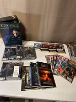 Four sealed NECA Terminator 2 figures in original packaging plus six paperback novels displayed on table