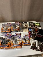 Full lot showing 6 Terminator Salvation action figures in original packaging and 5 related books on the right side.