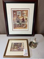 Framed large Trisha Romance print, smaller framed art print, and Star of Wonder ornament on stand shown together on a table.