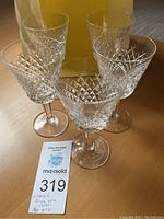 Five clear Waterford Alana claret wine glasses with diamond-cut pattern on bowls, arranged on a wood surface.