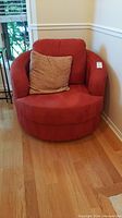 Front view of red swivel barrel chair with cushions in corner of room