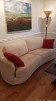 Front view of beige curved sofa with red toss cushions