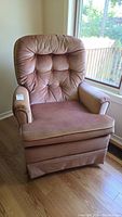 Full view of vintage fabric covered swivel rocking chair showing dusty rose fabric upholstery with some fading and wear.