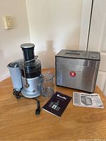 Full view of Breville juicer and Hamilton Beach bread maker with manuals on a wooden surface