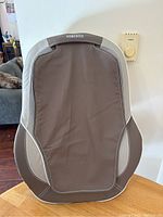 Front view of the Homedics back massager showing brown and beige fabric with mesh sections and the Homedics logo.