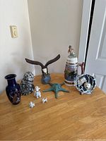 All 7 items arranged on a table showing animal and nature decor items including vase, eagle, beer stein, starfish, animal figurines, owl sculpture, and decorative bowl.