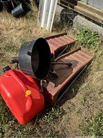 Photo of entire lot including red jerry can, black funnel, and red metal car ramps outdoors on grass.