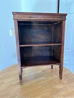 Front view of the small wooden shelf showing two open shelves, dark finish, and decorative scallop detail at the bottom.