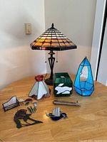 Photo of the stained glass lamp and 10 miscellaneous stained glass decorative pieces on a wooden table.