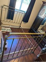 Vintage brass double bed frame parts leaning against the wall showing headboard and footboard.