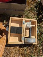 Wooden box with a large drill bit with round base and a silica gel packet inside.