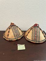 Two traditional 19th century woven conical hats from Borneo Sabah side by side on a dark surface with label in front.