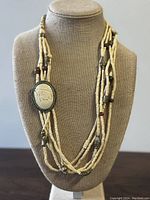 Front view of the necklace displayed on a bust stand showing the elephant carved pendant and the arrangement of beads.