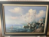 Framed oil painting showing a maritime harbor scene with sailboats, buildings, and seagulls under a cloudy sky.