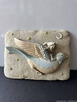 Front view of cast stone wall art plaque with angel on bird motif and starry sky background