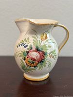 Front view showing floral pattern and gold trim on the spout and handle.