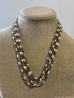 Front view of the vintage multi-strand cultured pearl necklace on mannequin bust showing alternating pearls and dark rectangular beads