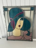 Front view of stained glass panel showing woman's face with blue hair, purple accents, and bird on shoulder