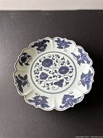 Top view of the white ceramic plate with blue floral and vine decoration, showing scalloped edge and central design.