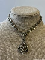 Front view of vintage Victorian Revival rhinestone necklace on display bust, showing square linked chain and floral drop pendant with clear rhinestones.