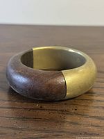 Photo showing the wooden and brass halves of the bangle with wood on the left side and brass on the right.