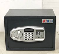 Image of black ALS branded safe box showing the front panel with electronic keypad, dial knob, and manual override keyhole.