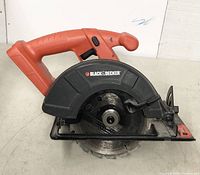 Front angled view of Black & Decker cordless circular saw with orange handle and black blade guard covering metal blade.