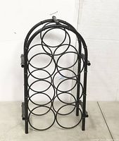 Front view of the black metal 7 bottle wine rack showing circular holders in a triangular arrangement.