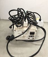 Front view of the rectangular metal growing light ballast with black electric cords coiled on top and ceramic socket visible.