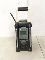 Front view showing LCD display, buttons, dial, and black rubber corner protectors.