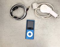 Photo showing a blue MP3 player, an auxiliary audio cable, and a white car charger cable on a light surface.