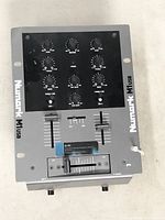 Top view of Numark M1usb DJ mixer showing controls and faders, unit is silver and black with branded logos.